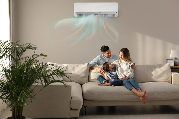 A family resting in a couch enjoying the coolness of their Air conditioner.
