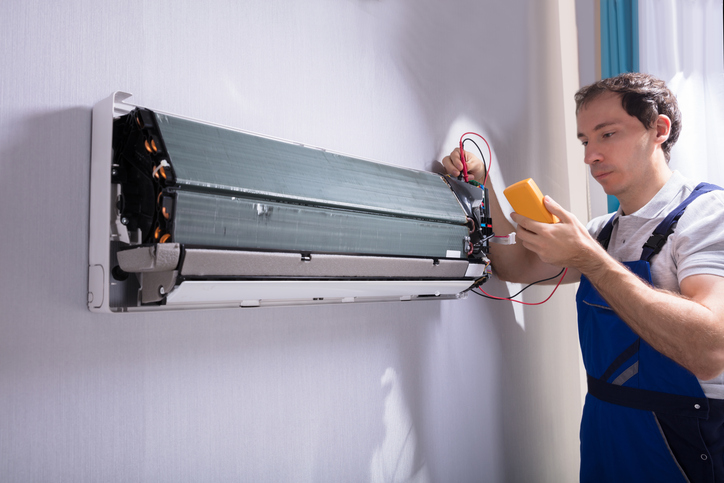 A technician is testing a air conditioner compressor.