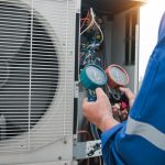 An HVAC specialist change the thermostat to the heat setting in getting heater ready for winter.