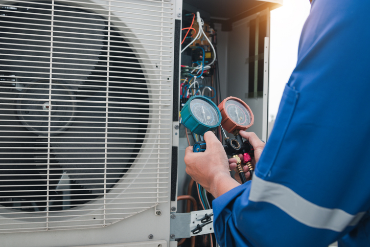 An HVAC specialist change the thermostat to the heat setting in getting heater ready for winter.