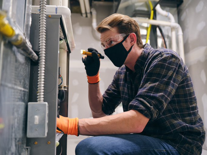 A technician is fixing a furnace that makes a high-pitched squeak.