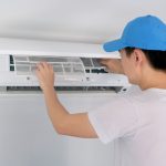 A male AC expert regularly cleans and changes the filters to prevent energy waste in the HVAC system.