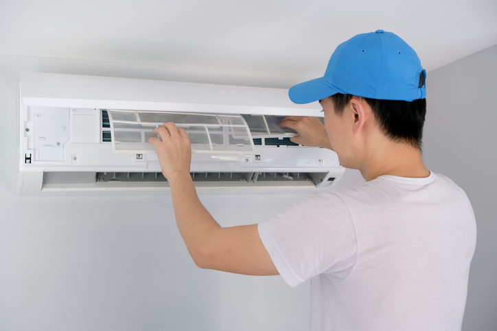 A male AC expert regularly cleans and changes the filters to prevent energy waste in the HVAC system.