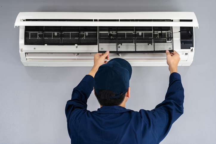 A technician performing annual maintenance to identify and fix issues such as clogged filters, refrigerant leaks, broken fans, etc.