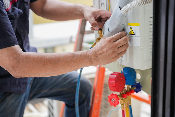 A professional technician demonstrating how to clean HVAC drain lines as part of regular maintenance.