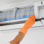 A man replacing an air filter as part of DIY HVAC maintenance tasks.