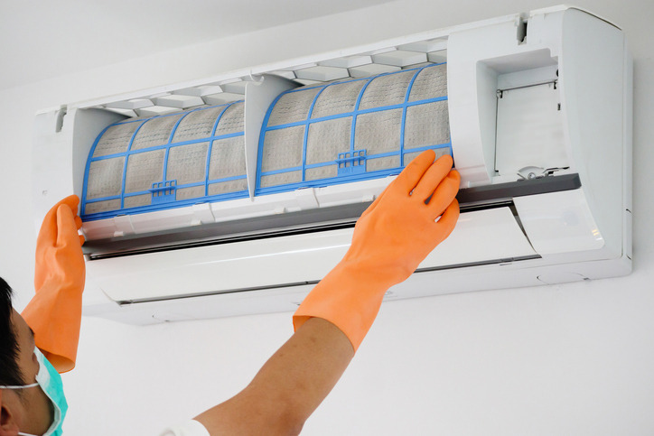 A man replacing an air filter as part of DIY HVAC maintenance tasks.