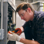 Professional HVAC technician inspecting a furnace control board to determine how much furnace repair will cost for a homeowner.
